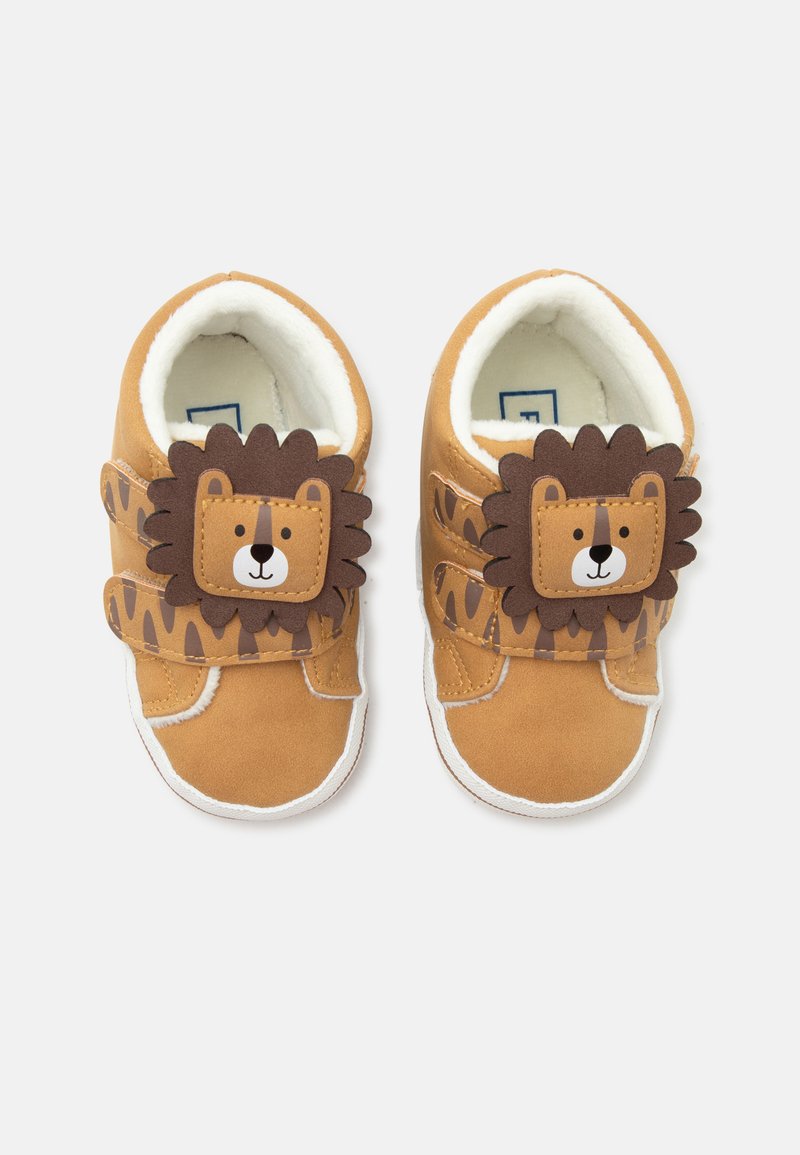 Chaussures marron pour tout-petits avec des visages et des crinières de lion sur les brides, doublure blanche douce et détails latéraux imprimés ressemblant à des taches.