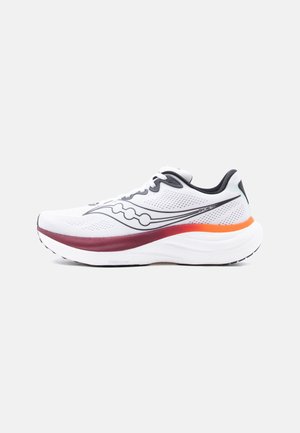 Balta sporta skriešanas kurpe ar melnu logotipu, tumši sarkaniem un oranžiem starpzoles akcentiem, un baltu zolīti uz vienkārša fona.