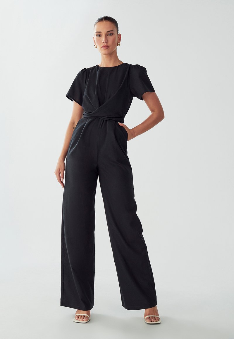 Zwarte jumpsuit met wijde pijpen, korte pofmouwen, een wikkelontwerp bij de taille en zijzakken. Soepele stof en minimalistische stijl.