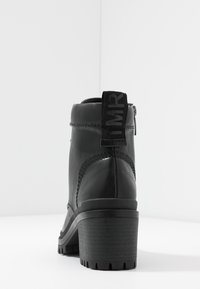 Musta nahkainen nilkkurit, joissa on massiivinen korko, teksturoidut sivupaneelit ja lenkitetty vetokahva. Varustettu sivuvetoketjulla ja uritetulla pohjalla.