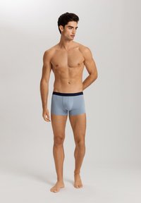 Ljusblå boxerkalsonger med midnattsblå midjeband som har varumärkestext. Slät textur, figurnära design och längd upp till mitten av låren.