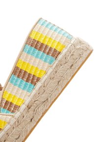 Geweven espadrille met een meerkleurig gestreept patroon in blauw, geel en bruin. Natuurlijke jutte zool met gevlochten details. Textielen bovenkant.