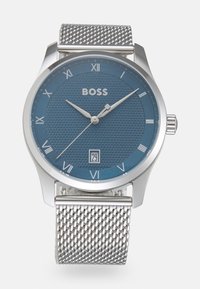 Silver mesh armbandsur med en texturerad blå urtavla, romerska siffersmarkörer och en datumvisning längst ner. Märkesnamnet "BOSS" framhävs tydligt.