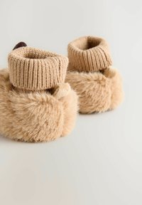 Chaussons en fausse fourrure couleur beige avec un revers en tricot, présentant un extérieur en fourrure douce et une texture agréable. Forme arrondie avec un minimum de détails.