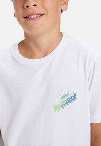 Bílé bavlněné tričko s barevným logem Quiksilver v zelených a modrých tónech. Design s kulatým výstřihem, krátké rukávy, jemná textura.