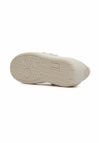 Semelle de sneaker de couleur claire avec une texture, présentant un grip à motifs comprenant des designs circulaires et triangulaires. La marque est visible sur le côté.