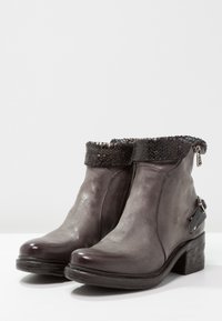 Graue Leder-Stiefeletten mit einer strukturierten, schwarzen Schlangenlederverzierung, seitlichem Reißverschluss und einem niedrigen Blockabsatz. Mit einem dekorativen Metallakzent.