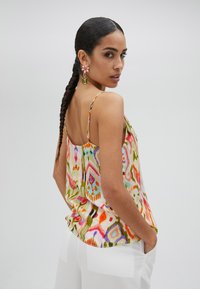 Top senza maniche multicolore in tessuto leggero. Presenta motivi astratti in rosa, verde, arancione e viola. Design elegante sulla schiena.