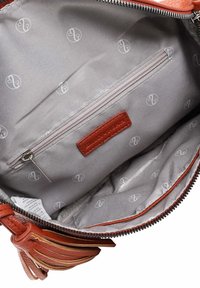 Interno di una borsa in pelle marrone con una fodera grigia caratterizzata da un motivo a logo, una tasca con zip e un'etichetta interna. Hardware della cerniera visibile.