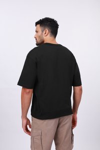 T-shirt noir en coton avec une coupe décontractée, des manches courtes et un col rond. Design simple, tissu texturé, met en valeur des détails de couture.
