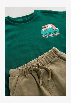 Sweat-shirt vert avec un graphique "AVENTURE EN PLEIN AIR" et un pantalon de survêtement beige avec une taille élastique et un cordon de serrage. Texture de tissu lisse.