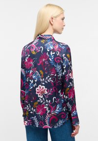 Blusa floreale in satin navy con intricate fantasie rosa, blu e giallo. Presenta maniche lunghe e un orlo rotondo. Vestibilità regolare.