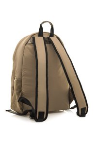 Sac à dos tan en tissu rembourré, avec des bretelles noires et une poignée texturée sur le dessus. Il comporte une poche latérale et des accents cousus en bas.