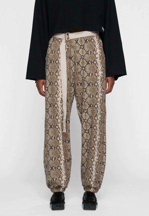 Pantaloni a stampa serpente marrone con una cintura beige. Presentano un polsino elasticizzato e gambe larghe, realizzati in un materiale leggero.