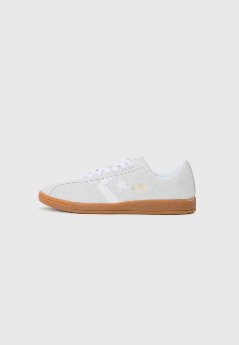 White suede sneakers with a gum sole. Features a white star logo and "ALL STAR" in gold on the side. Rounded toe and lace-up design.
