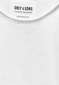 Biała bawełniana koszulka z okrągłym dekoltem, teksturowanym materiałem oraz czarną metką z napisem "ONLY & SONS" i informacjami o pielęgnacji.