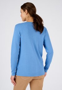 Maglione blu a maniche lunghe realizzato in morbido tessuto a maglia, con colletto a girocollo e orlo dritto, abbinato a pantaloni beige.