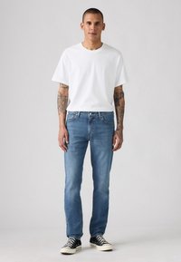 Hvit bomull t-skjorte kombinert med lyseblå denimjeans. Har en avslappet passform med rette ben, enkelt design og klassisk fem-lommers stil.