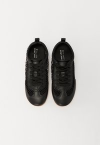 Czarne wegańskie sneakersy z panelami z siateczki, okrągłym noskiem i płaskimi sznurowadłami. Posiadają pętlę na pięcie ułatwiającą zakładanie oraz teksturowaną powierzchnię.