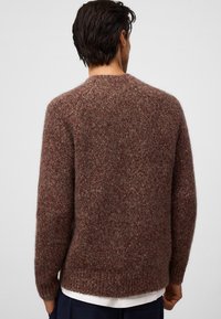 Bordowy sweter z dzianiny, wykonany z puszystej przędzy, ma okrągły dekolt i ściągacze, charakteryzuje się teksturowaną powierzchnią oraz luźnym krojem.