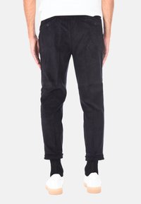 Pantaloni in corduroy neri con righe verticali, fit slim, lunghezza leggermente cropped, dotati di due tasche posteriori e orlo pulito.