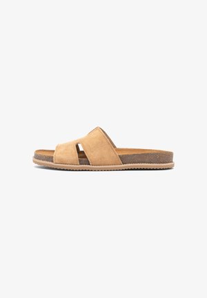 Tan suede slide sandal with crisscross straps, cork footbed, and beige rubber sole, shown in side view on white background.