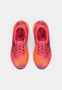 Nike tenisice za trčanje u gradijentnoj ružičastoj i narančastoj boji, sa prozračnim mrežastim gornjim dijelom, teksturiranom površinom i crnim akcentima logotipa.