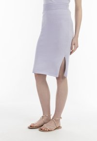 Licht lavendelkleurige knie-lange rok van zachte stof, met een zijsplits en een geribde tailleband. Gecombineerd met gouden sandalen met banden.