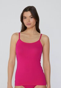 Top sin mangas fucsia con tirantes finos, hecho de una tela suave y elástica. Presenta un diseño ajustado y un escote redondeado.