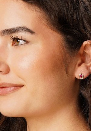 Gold stud earrings featuring a round design with a central pink gemstone surrounded by small clear stones, highlighting intricate detailing.