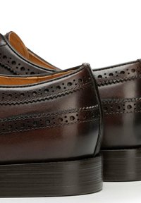 Braune Lederschuhe mit perforierten Akzenten und glatter Oberfläche, abgerundeter Spitze und geschichtetem Absatz.