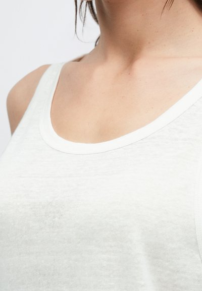 Άσπρο, αμάνικο τοπ με στρογγυλή λαιμόκοψη. Κατασκευασμένο από απαλό, ελαφρύ υλικό με ελαφρώς υφή φινίρισμα. Απλός σχεδιασμός, χωρίς σχέδια.