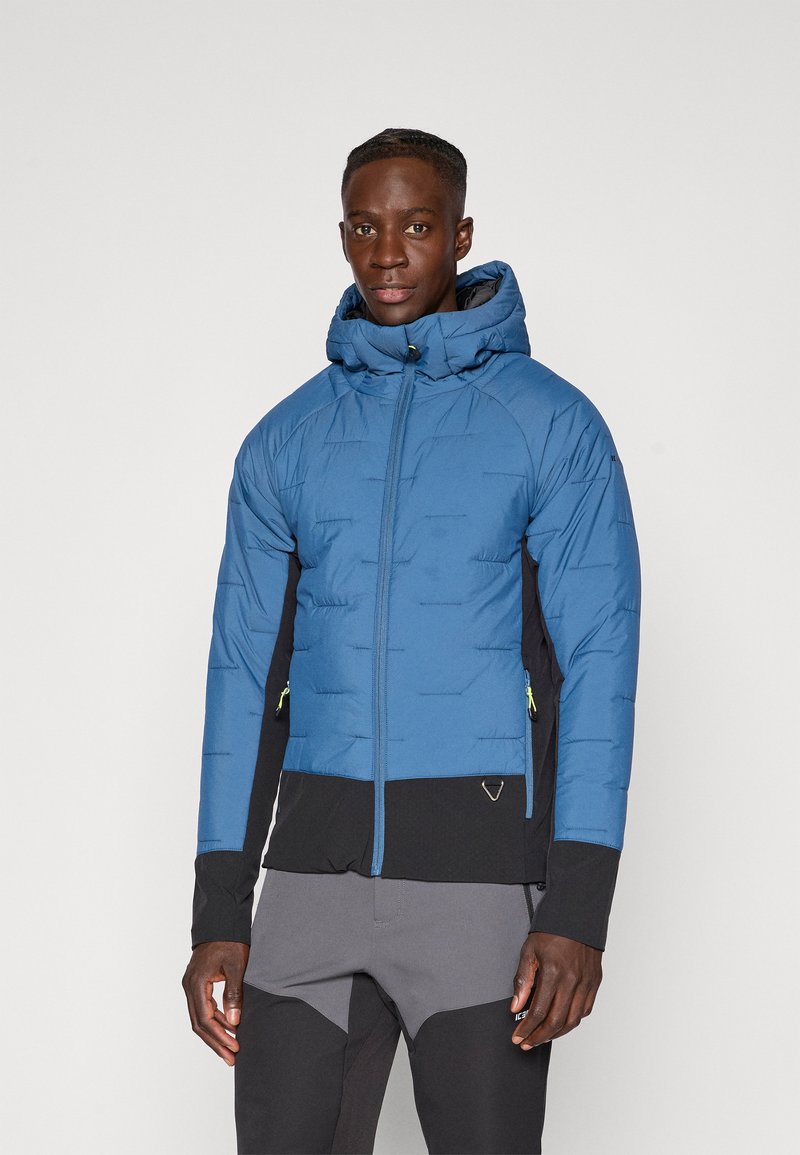 Giacca blu imbottita con zip frontale, cappuccio e dettagli neri. Presenta un materiale testurizzato e zip verdi a contrasto.
