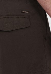 Brune shorts med et tekstureret stof, der har en baglomme og VOLCOM mærkets tag. Designet inkluderer diskrete lodrette linjer.