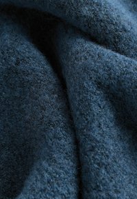 Donkerblauwe stof met een zachte, gestructureerde textuur, met een fluffige uitstraling en een licht geweven patroon. Ideaal voor gezellige kleding of dekens.