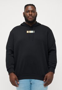 Sudadera con capucha negra de corte recto, con un logo en bloques de colores en el centro. Tejido suave con puños y dobladillo acanalados.