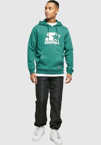 Chabrowa bluza z kapturem z białym logo "STARTER", zaciągany kaptur i kieszeń z przodu; w zestawie z czarnymi spodniami i białymi trampekami. Prosty, codzienny design.