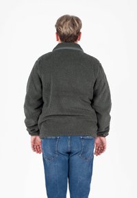 Giacca in fleece verde scuro con colletto, tessuto testurizzato e polsini elasticizzati. Indossata sopra un paio di jeans blu, vista da dietro.