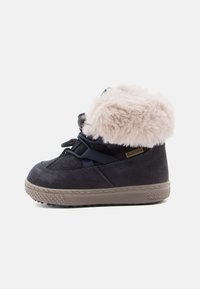 Bottine en suede noire avec un revers en fausse fourrure beige, design à lacets contrastants et semelle en caoutchouc texturée. Dispose d'une étiquette imperméable.