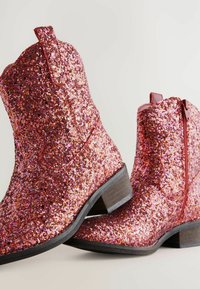 Bottines à paillettes roses et rouges avec un petit talon en bois, fermeture éclair et coutures décoratives de style western sur une surface lisse.