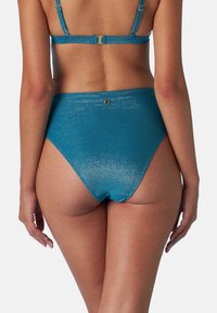 Costumi da bagno a vita alta in tessuto metallizzato color teal, con una texture liscia, caratterizzati da una leggera brillantezza e un piccolo logo dorato sul retro.