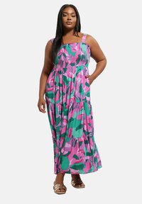 Maksimekko, joka on valmistettu kevyestä kankaasta ja jossa on värikäs vaaleanpunainen ja vihreä abstrakti kuvio, smokkibodice ja olkaimet.