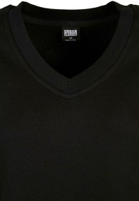 Musta V-kaelusega T-särk, mis on valmistatud pehmest kangast. Omab soonikuga kaelust ja siseriiet, kus on kiri "Urban Classics" ning suurus XS.