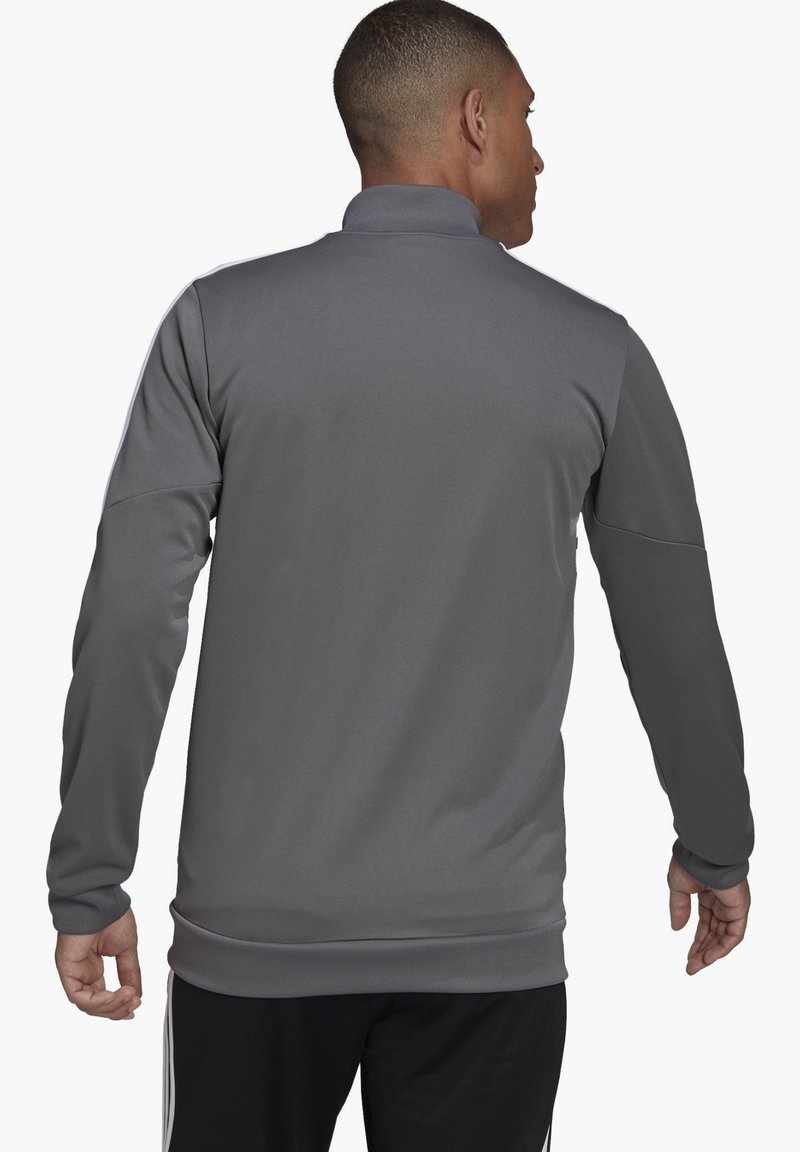 Grau sportliche Jacke mit hohem Kragen, langen Ärmeln und glatter Textur. Verfügt über schwarze Akzente entlang der Schultern und Bündchen.