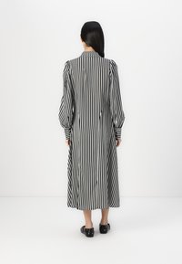 Μαύρο και άσπρο ριγ�έ μακρύ φόρεμα με φουσκωτά μανίκια, κλείσιμο με κουμπί και ίσια γραμμή. Υφασμάτινη επιφάνεια με λεία υφή.