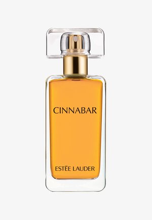 Bouteille de parfum en verre carré avec un capuchon transparent, contenant un liquide ambré. Présente un texte noir en gras indiquant "CINNABAR" et "ESTÉE LAUDER."