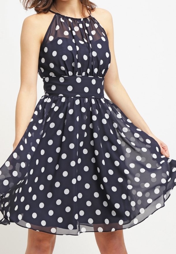 Robe à pois bleu marine avec des points blancs. Fabriquée en tissu léger, elle présente un col halter et une taille cintrée. Jupe évasée.