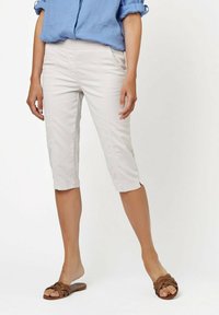 Helle beige Capri-Hosen mit einer taillierten Passform und weicher Textur, mit Seitennähten und knöchellanger Länge. Kombiniert mit braunen flachen Sandalen.