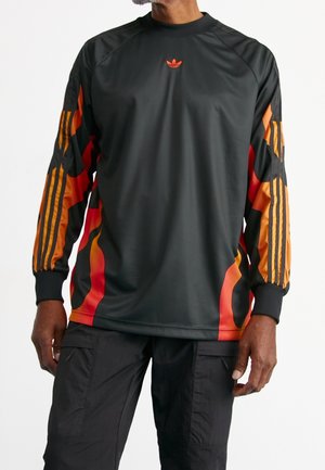 T-shirt noir à manches longues avec des graphiques de flammes orange et rouges sur les manches, arborant le logo Adidas sur la poitrine et des poignets côtelés.