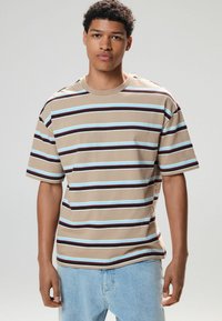 Beige kortærmet t-shirt med horisontale striber i brun og lys blå. Har en rund halsudskæring og en afslappet pasform.
